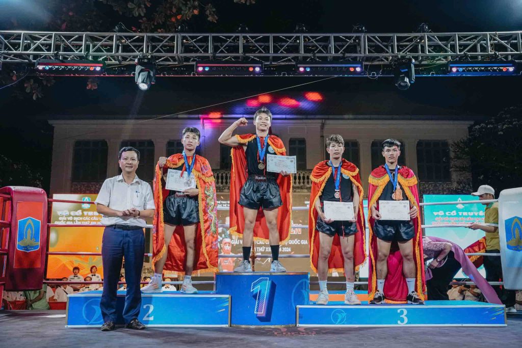 VĐV Thế Toàn đứng ở vị trí số 1 trên bục vinh quang cao nhất, rạng rỡ và đầy tự hào khi cầm tấm bằng khen và đeo tấm HCV quốc gia