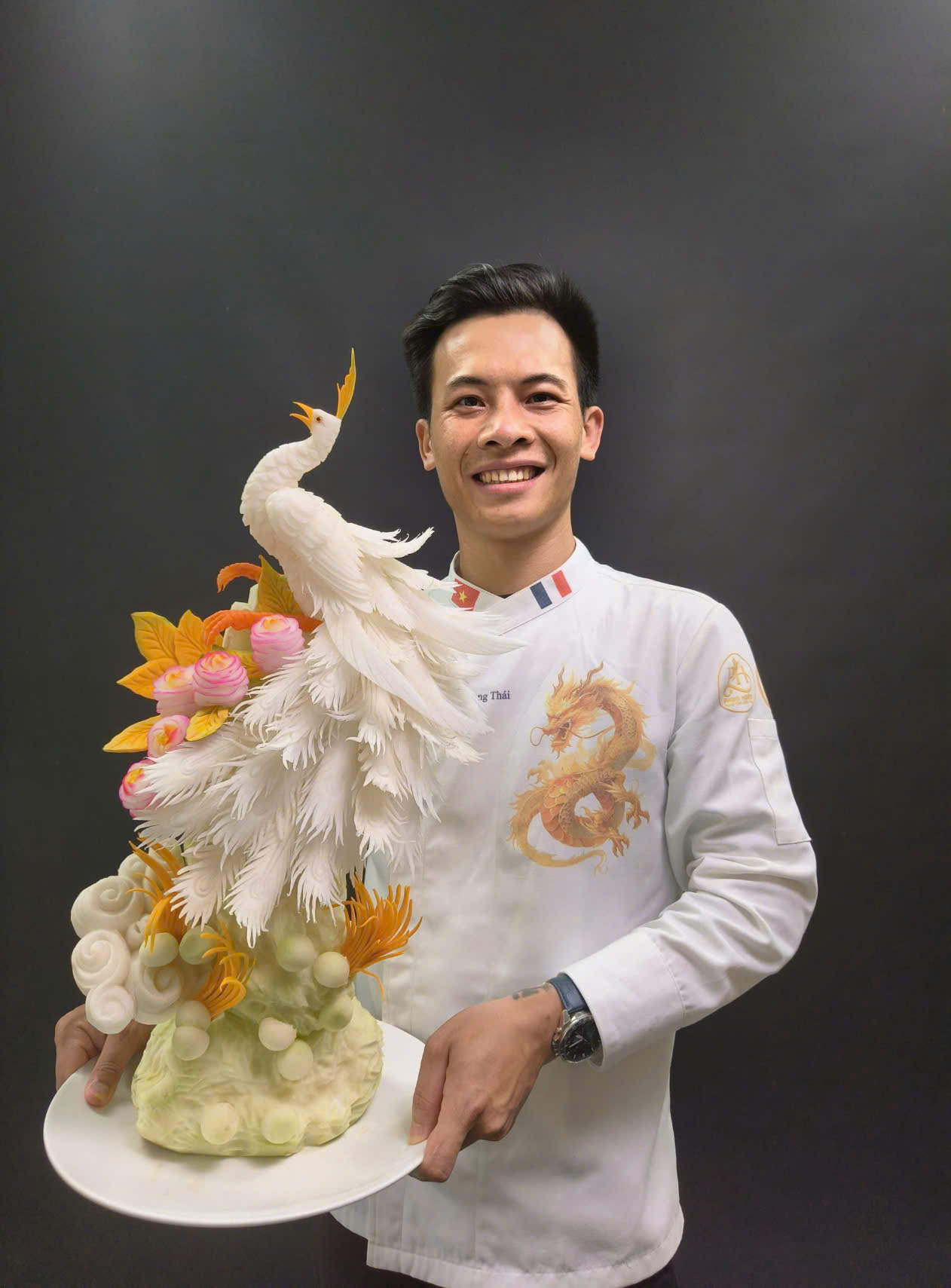 Bếp trưởng Bùi Quang Thái bên tác phẩm chim trĩ được điêu khắc hoàn toàn từ rau củ quả, thể hiện kỹ thuật và sự sáng tạo trong nghệ thuật cắt tỉa